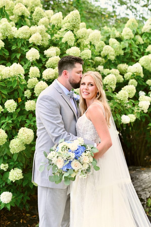 Bride and groom among white hydrangeas