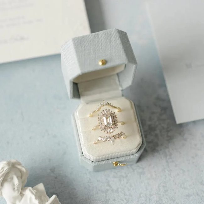 TheHeirloomWedding pale gray linen octagon ring box open to show an emerald-cut ring