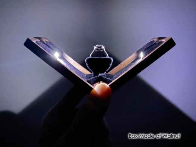 Wanderweg X-braced walnut ring box open flat with LED lights shining on a ring